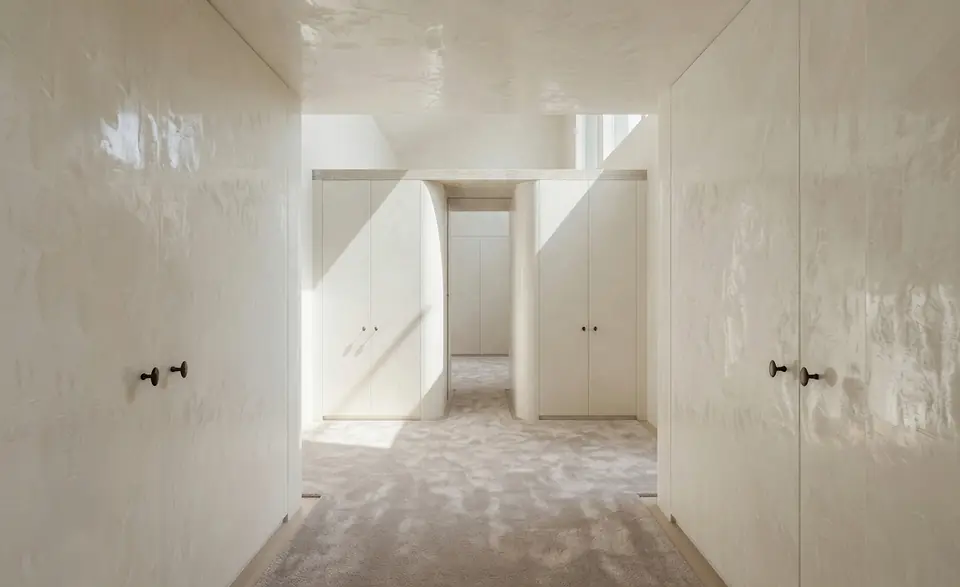 Dressing hall. Midcentury Renovation, private residence in Old Westbury, NY: a corridor of lacquered plaster wardrobes with bronze knobs, rounded jambs and carpet