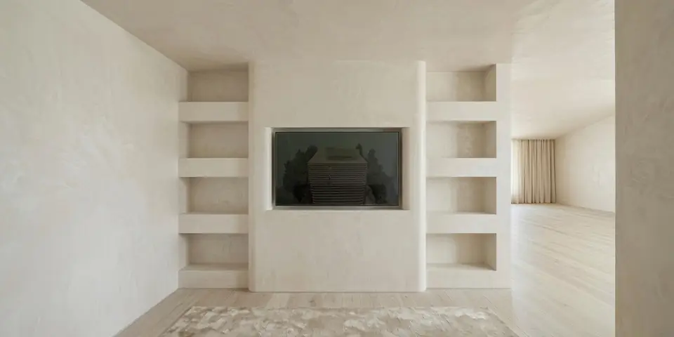 Media wall. Midcentury Renovation, private residence in Old Westbury, NY: a plaster media wall with a rounded-edge central TV niche, open plaster shelving, oak floors and a shag rug